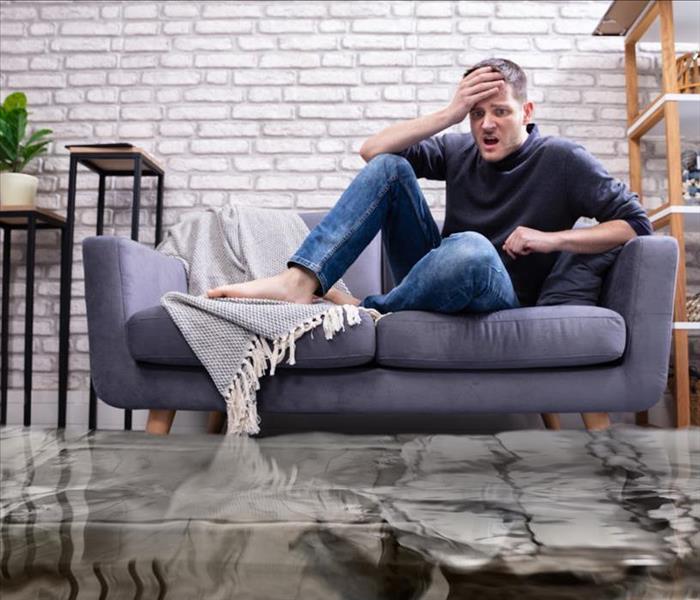 guy floating on couch in flooded living room